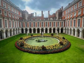 An interior courtyard of the Hampton Court Palace, featuring a fountain surrounded by a circular flower bed.