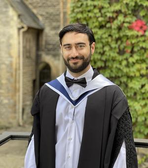 Photo of student Hashemipour on his graduation day, standing in front of an old college