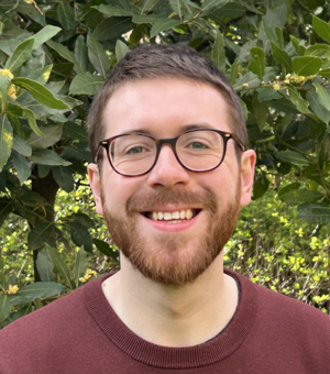Portrait photo of student White wearing glasses and smiling at the camera