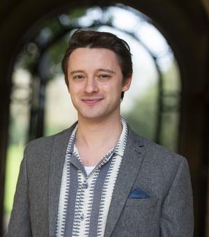 Head and shoulders portrait of a student Koubis, with blurred archway in the background in an outdoor setting